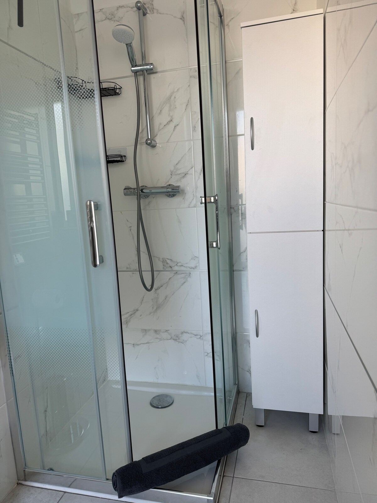 Glass shower cabin with marble tiles